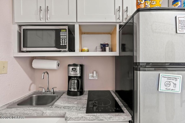 kitchen with light stone countertops, sink, white cabinetry, and stainless steel appliances