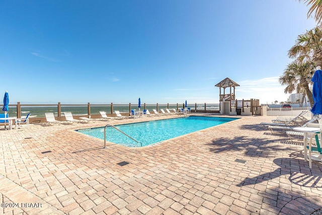 view of pool featuring a water view and a patio area