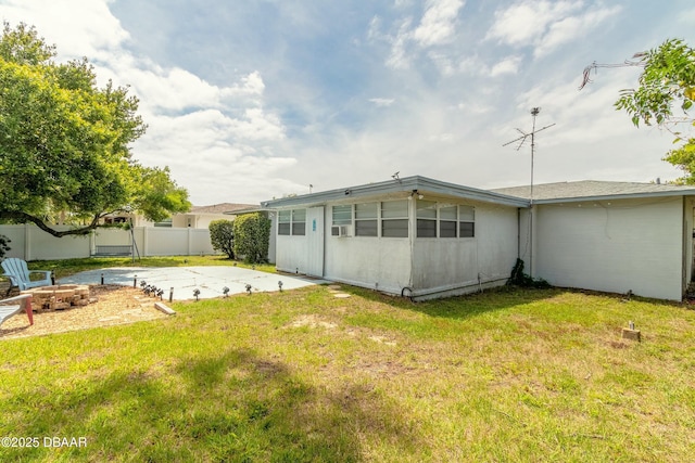 back of property with a fire pit, a yard, and a patio area