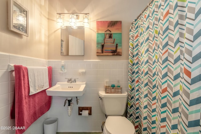 bathroom featuring toilet, tile walls, sink, and curtained shower