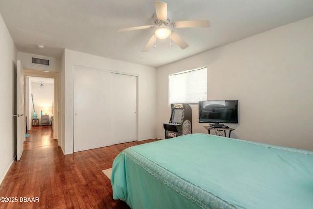 bedroom with ceiling fan, dark hardwood / wood-style flooring, and a closet