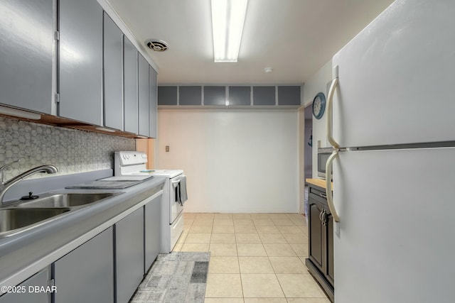 kitchen with white appliances, light tile patterned floors, decorative backsplash, gray cabinetry, and sink