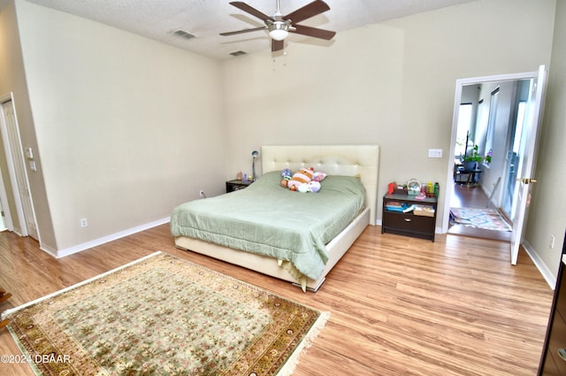 bedroom featuring ceiling fan, light hardwood / wood-style flooring, and a textured ceiling