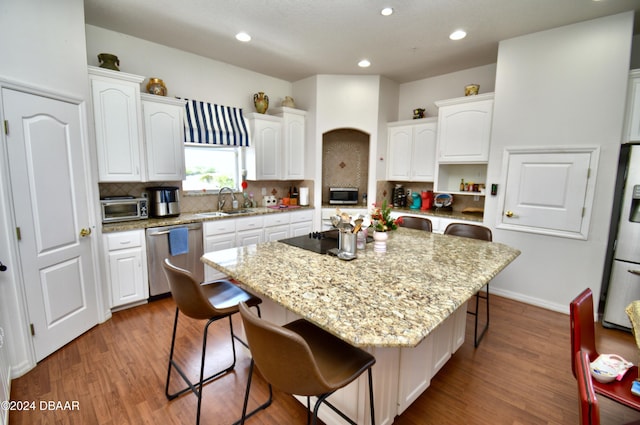 kitchen with a breakfast bar, a center island, white cabinets, hardwood / wood-style flooring, and appliances with stainless steel finishes