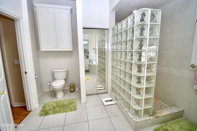 bathroom featuring a shower, tile patterned flooring, a textured ceiling, and toilet