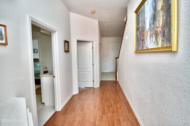 corridor featuring light hardwood / wood-style floors and a textured ceiling