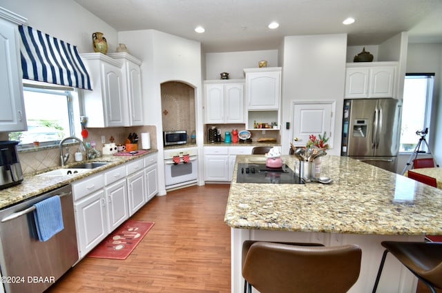 kitchen featuring white cabinets, a center island, light wood-type flooring, and appliances with stainless steel finishes