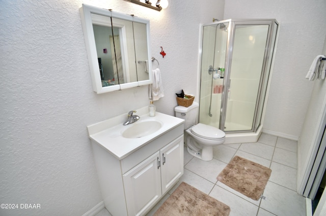 bathroom with tile patterned flooring, vanity, a shower with shower door, and toilet