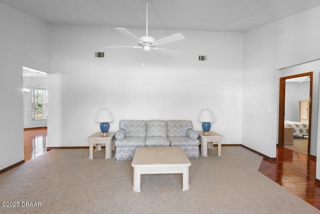 carpeted living room with high vaulted ceiling, visible vents, and baseboards