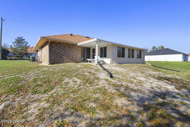 back of property with a yard, cooling unit, and brick siding