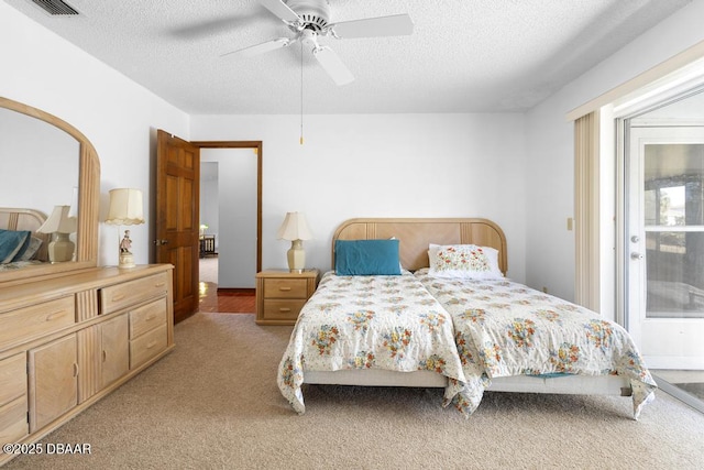 bedroom featuring a ceiling fan, light carpet, visible vents, and a textured ceiling