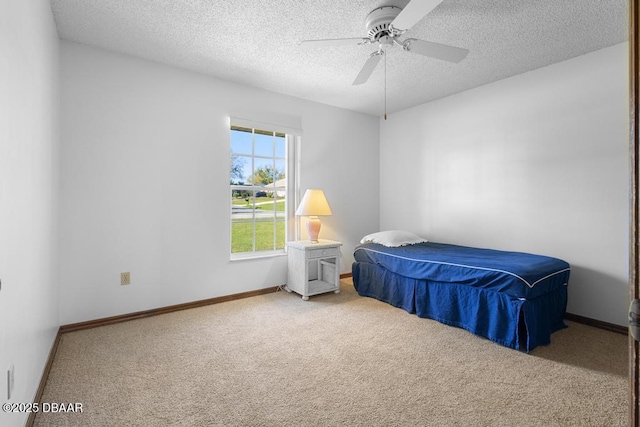 carpeted bedroom with a textured ceiling, ceiling fan, and baseboards