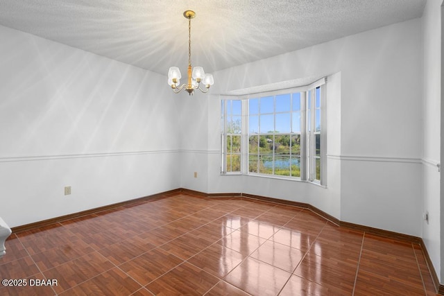 empty room featuring a notable chandelier, baseboards, and a textured ceiling