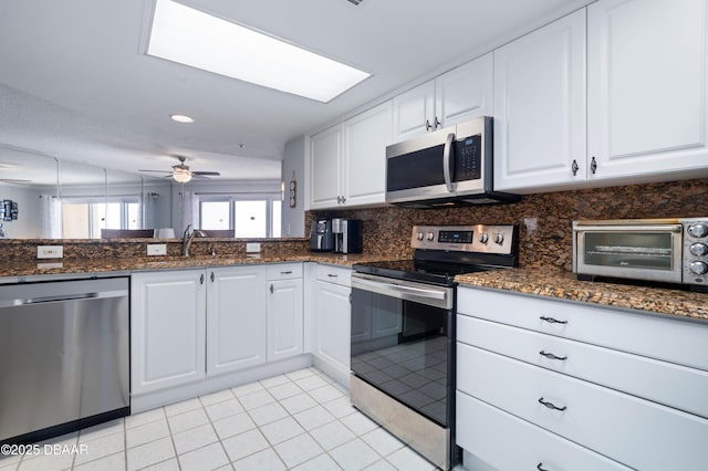 kitchen with a toaster, stainless steel appliances, white cabinets, ceiling fan, and a sink