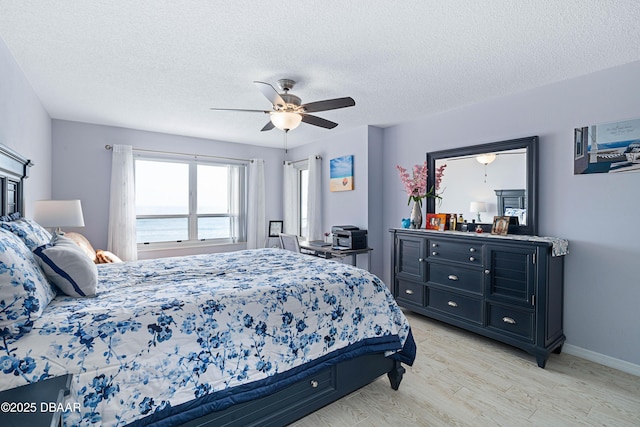 bedroom with baseboards, ceiling fan, light wood-style floors, and a textured ceiling