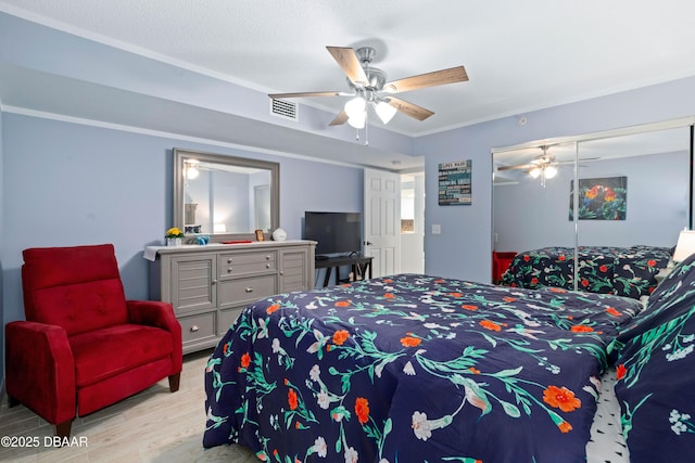 bedroom featuring wood finished floors, a closet, ornamental molding, ceiling fan, and visible vents