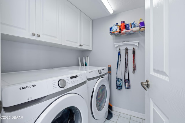 clothes washing area featuring light tile patterned flooring, washer and dryer, cabinet space, and baseboards