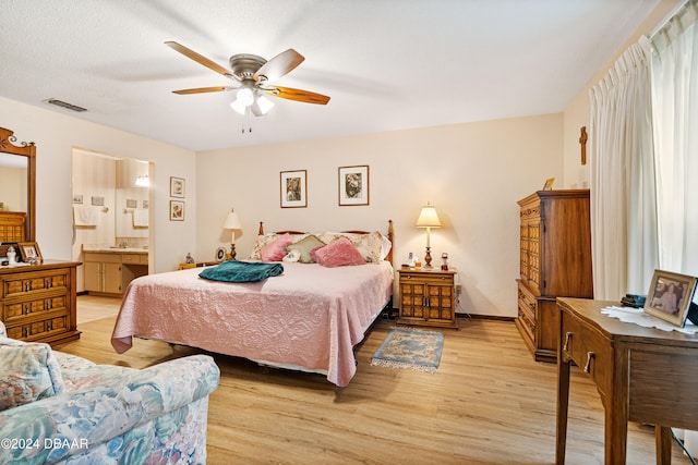 bedroom with light wood-type flooring, ensuite bathroom, and ceiling fan