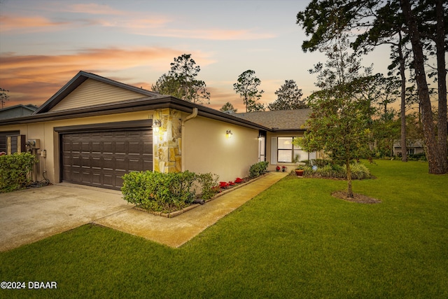 ranch-style home featuring a lawn and a garage