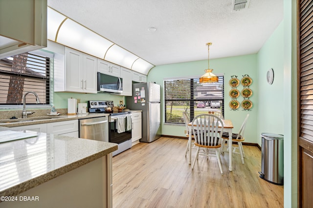 kitchen with appliances with stainless steel finishes, sink, light hardwood / wood-style floors, white cabinetry, and hanging light fixtures