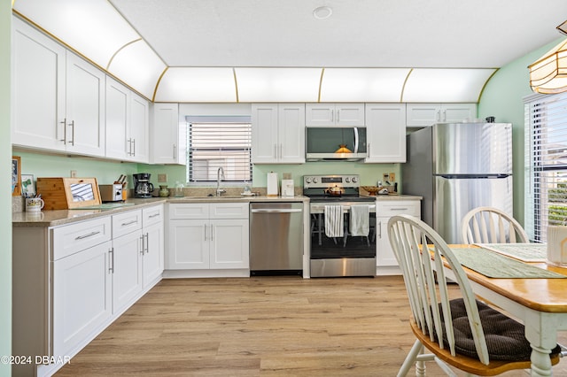 kitchen featuring light stone countertops, sink, stainless steel appliances, light hardwood / wood-style floors, and white cabinets