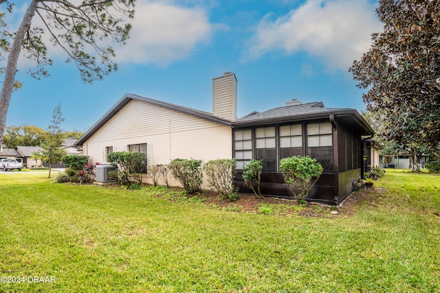 back of property with a sunroom, a yard, and central AC