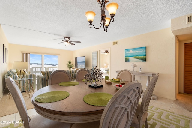 tiled dining area with ceiling fan with notable chandelier and a textured ceiling