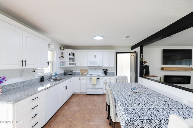 kitchen featuring white appliances, a fireplace, white cabinetry, sink, and light stone counters