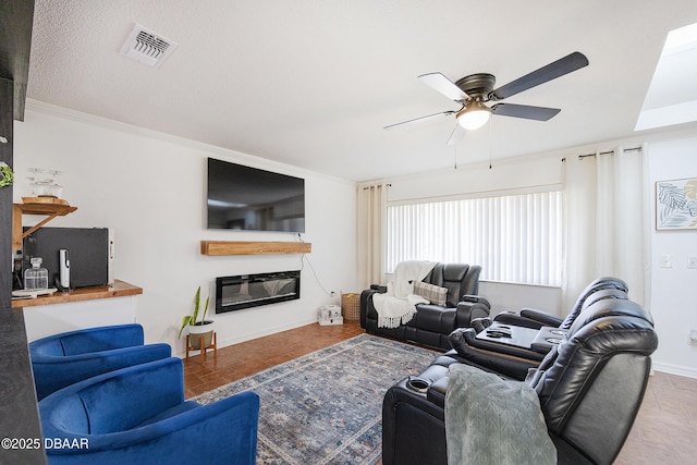 living room with a textured ceiling, ceiling fan, and ornamental molding