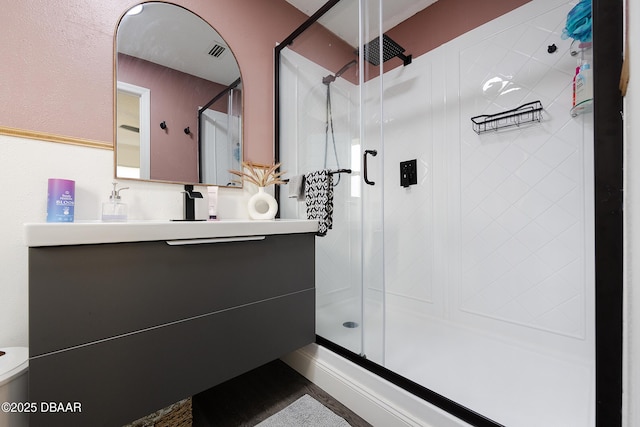 bathroom with toilet, a shower with shower door, and vanity