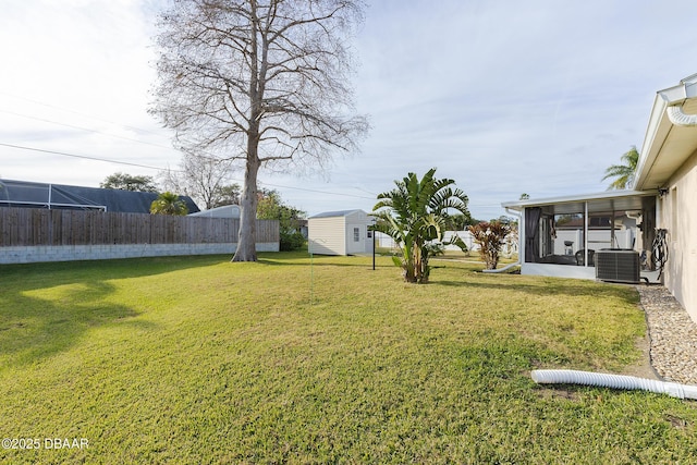 view of yard featuring a storage unit, central AC, and a sunroom