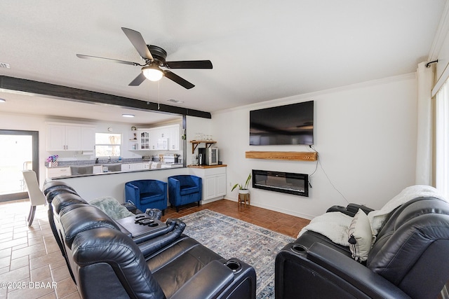 living room with ceiling fan, beamed ceiling, and ornamental molding