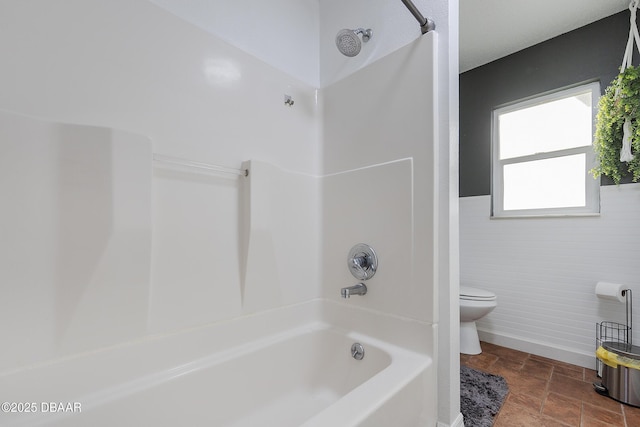 bathroom featuring toilet, bathtub / shower combination, and tile walls