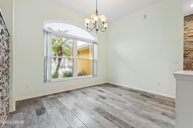 unfurnished dining area featuring a chandelier and light hardwood / wood-style floors