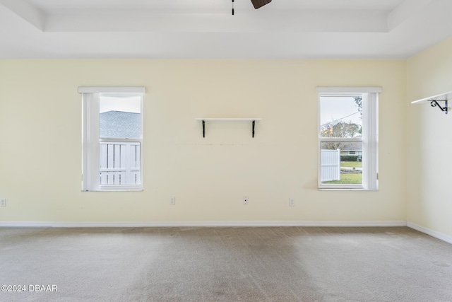 carpeted empty room featuring a raised ceiling and ceiling fan