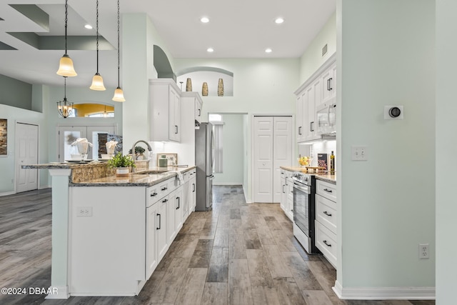 kitchen featuring stainless steel appliances, sink, pendant lighting, dark stone countertops, and white cabinets