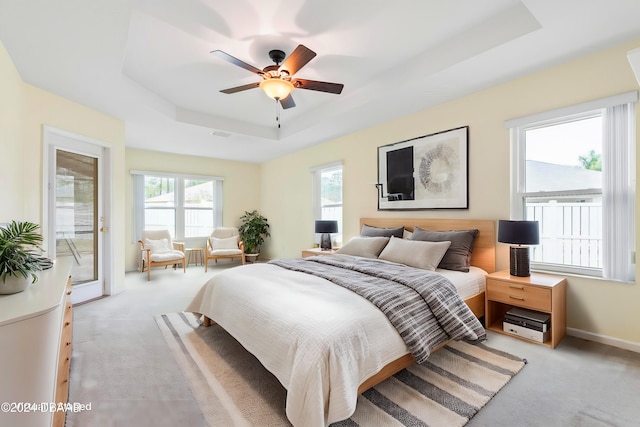 carpeted bedroom featuring access to outside, a raised ceiling, and ceiling fan