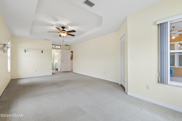 unfurnished room with light carpet, a raised ceiling, and ceiling fan