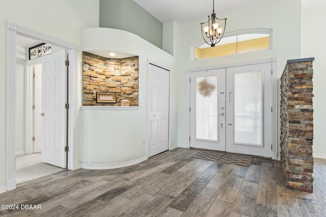 foyer entrance with hardwood / wood-style floors, an inviting chandelier, a high ceiling, and french doors