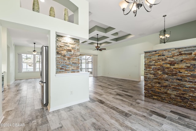 unfurnished living room featuring hardwood / wood-style floors, ceiling fan with notable chandelier, and a wealth of natural light