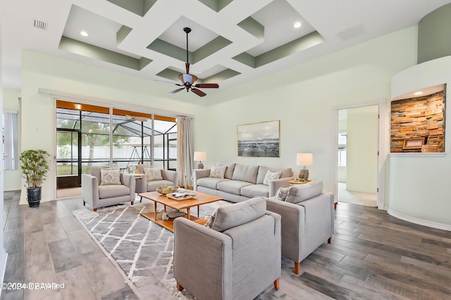 living room featuring hardwood / wood-style flooring, ceiling fan, a high ceiling, and coffered ceiling