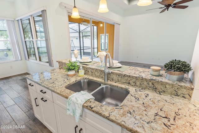 kitchen with white cabinets, sink, ceiling fan, decorative light fixtures, and light stone counters