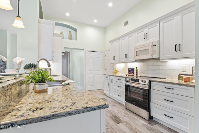 kitchen featuring light stone countertops, stainless steel appliances, sink, pendant lighting, and white cabinetry