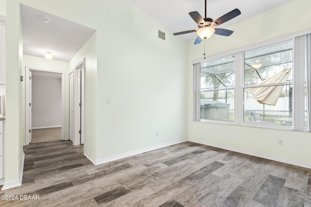 empty room featuring ceiling fan, plenty of natural light, vaulted ceiling, and hardwood / wood-style flooring