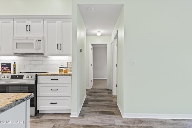 kitchen with white cabinets, light stone countertops, electric stove, and tasteful backsplash