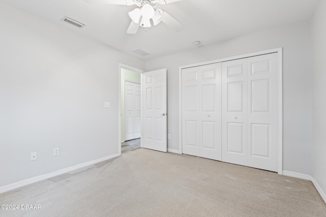 unfurnished bedroom with ceiling fan, light colored carpet, and a closet