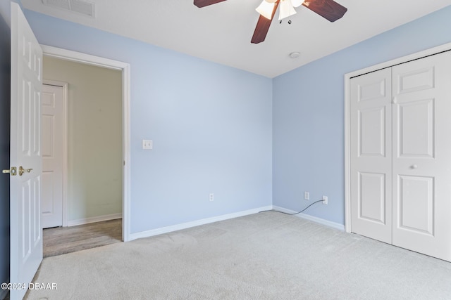 unfurnished bedroom with ceiling fan, light colored carpet, and a closet