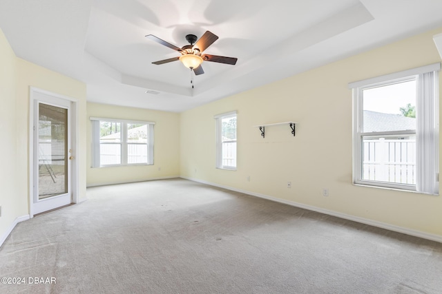 empty room featuring a tray ceiling, ceiling fan, and light colored carpet