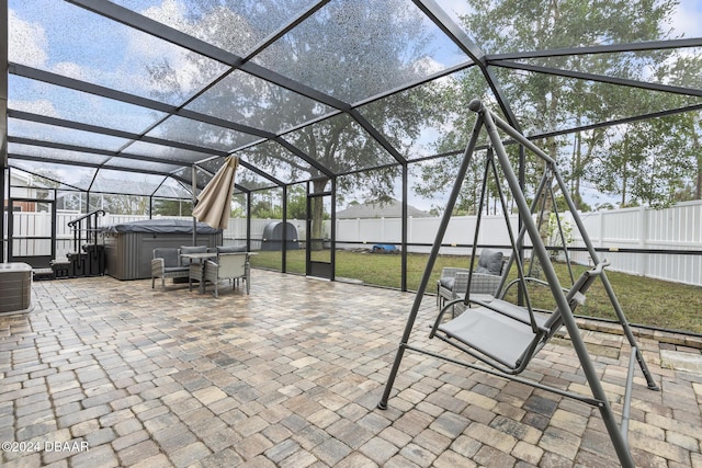 view of patio with glass enclosure, cooling unit, and a hot tub