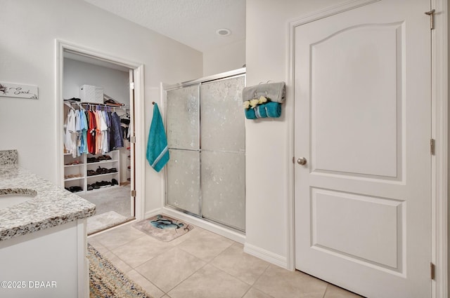 316 Nowell Loop, Deland, FL 32724 - full bathroom with a shower stall, tile patterned flooring, a walk in closet, vanity, and a textured ceiling